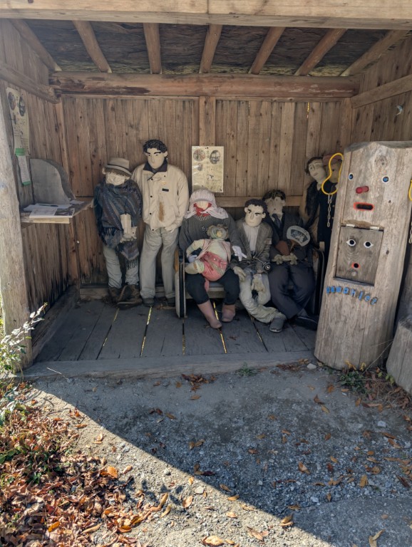 A small shed packed with a group of scarecrows arranged like a family