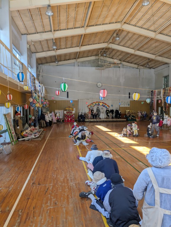 Rows of scarecrows filling the gymnasium, each with distinct clothing and poses